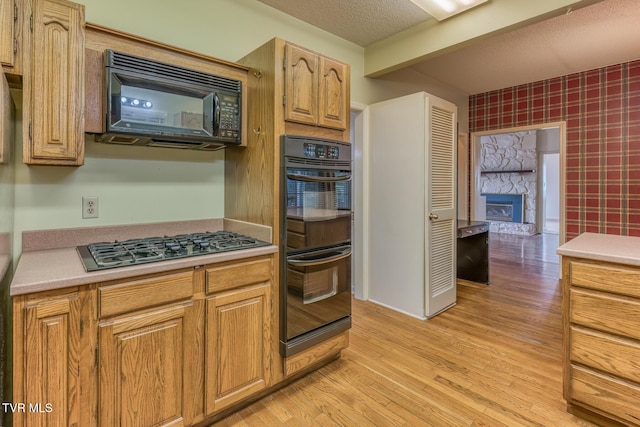 3510 Bondwood Cir, Johnson City, TN 37604 - kitchen featuring black appliances, wallpapered walls, light countertops, light wood finished floors, and a stone fireplace