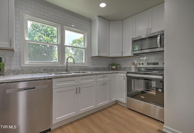 2221 Elizabethton Hwy, Johnson City, TN 37601 - kitchen with appliances with stainless steel finishes, a sink, light wood-style flooring, white cabinetry, and plenty of natural light