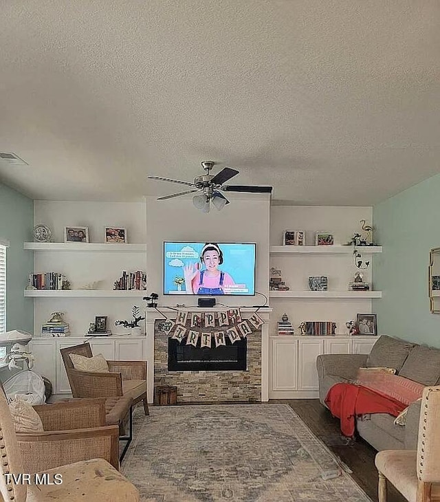 1202 Raccoon Ln, Piney Flats, TN 37686 - living room featuring a textured ceiling, a ceiling fan, wood finished floors, a fireplace, and built in features