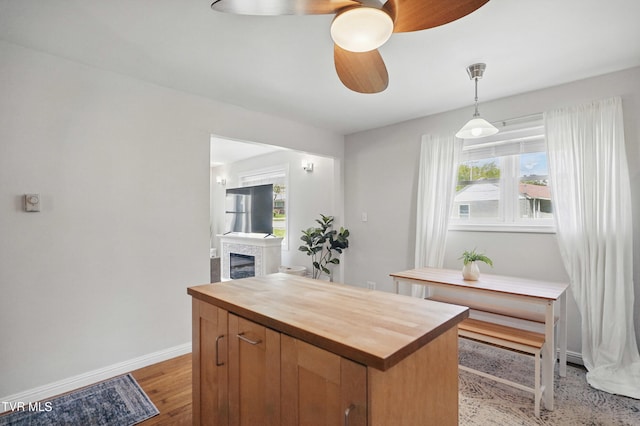 744 NE Hurricane Rd, Wise, VA 24293 - kitchen featuring butcher block countertops, a ceiling fan, baseboards, a fireplace, and light wood-style flooring