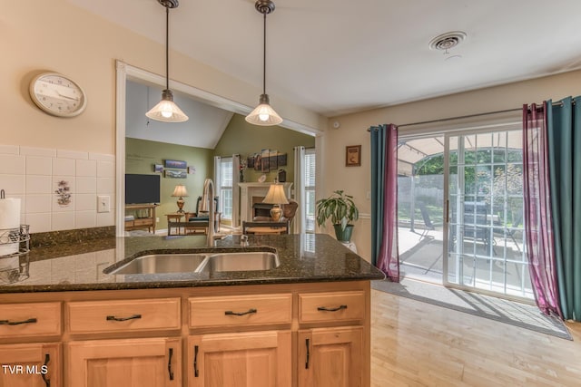 620 Glen Oaks Pl, Johnson City, TN 37615 - kitchen featuring a sink, vaulted ceiling, dark stone countertops, hanging light fixtures, and light wood-style floors