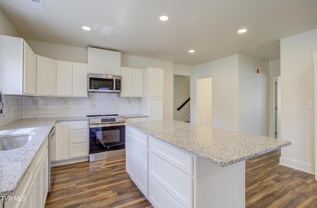 408 Levelin St, Erwin, TN 37650 - kitchen with appliances with stainless steel finishes, dark wood-type flooring, a center island, backsplash, and white cabinetry