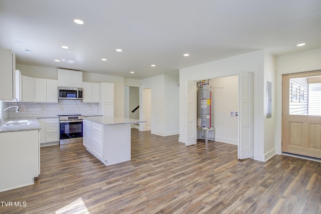 408 Levelin St, Erwin, TN 37650 - kitchen with appliances with stainless steel finishes, electric water heater, decorative backsplash, wood finished floors, and white cabinets