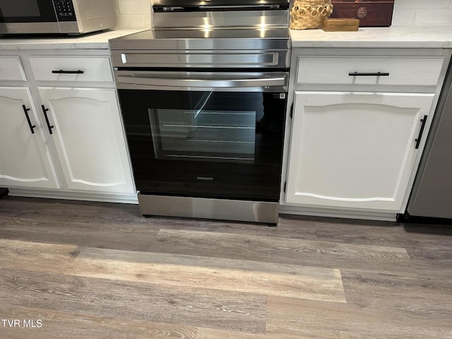 516 Fleetwood Ct Unit F, Kingsport, TN 37660 - kitchen view of stainless steel range with electric cooktop, black microwave, wood finished floors, and white cabinets