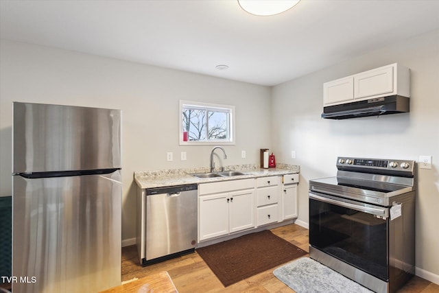 515 Aesque St Ext, Kingsport, TN 37665 - kitchen with appliances with stainless steel finishes, a sink, under cabinet range hood, light wood finished floors, and white cabinetry