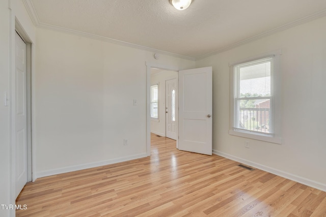 523 W Main St, Johnson City, TN 37604 - unfurnished bedroom with multiple windows, crown molding, light wood finished floors, baseboards, and a textured ceiling