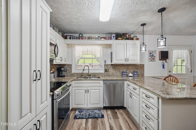 5009 Surrey Dr, Kingsport, TN 37664 - kitchen featuring appliances with stainless steel finishes, a sink, a peninsula, light wood-type flooring, and white cabinets