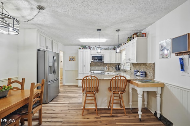 5009 Surrey Dr, Kingsport, TN 37664 - kitchen with appliances with stainless steel finishes, a peninsula, light wood-type flooring, white cabinetry, and light stone countertops