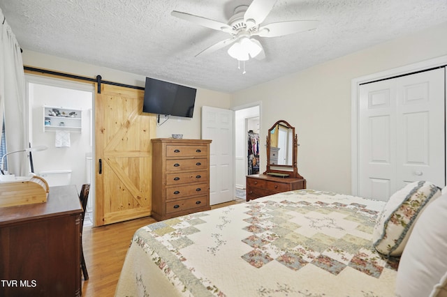 5009 Surrey Dr, Kingsport, TN 37664 - bedroom with light wood finished floors, a closet, a textured ceiling, a barn door, and ceiling fan