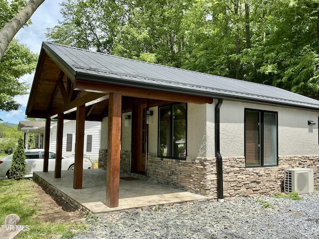 153 Hampton Creek Rd, Roan Mountain, TN 37687 - view of property exterior with ac unit, stone siding, stucco siding, metal roof, and a patio