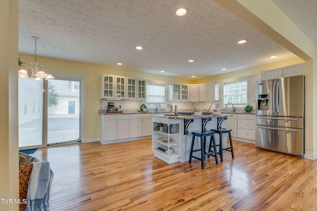 516 Bowmantown Rd, Telford, TN 37690 - kitchen featuring stainless steel fridge, light wood finished floors, a kitchen bar, open shelves, and white cabinetry