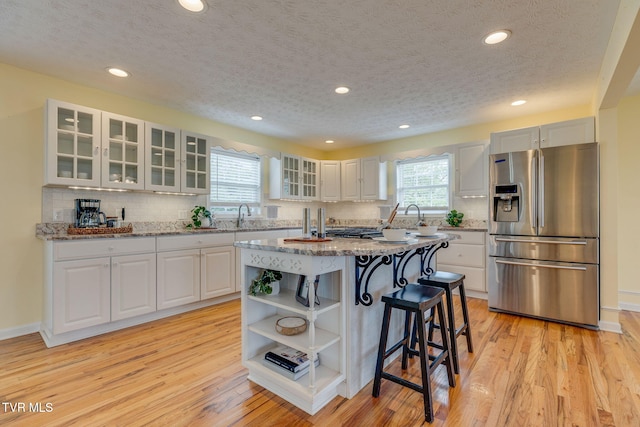 516 Bowmantown Rd, Telford, TN 37690 - kitchen featuring stainless steel fridge with ice dispenser, open shelves, a kitchen breakfast bar, light wood finished floors, and recessed lighting