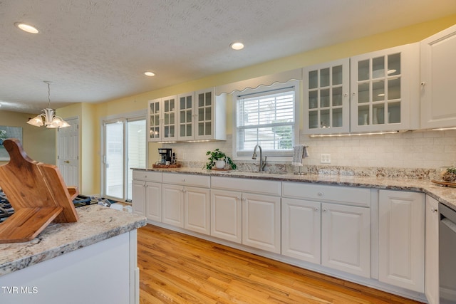 516 Bowmantown Rd, Telford, TN 37690 - kitchen featuring light wood finished floors, a sink, tasteful backsplash, white cabinets, and decorative light fixtures