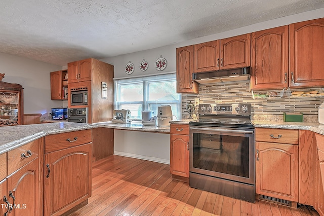 481 Pleasant Hill Rd, Blountville, TN 37617 - kitchen featuring stainless steel appliances, under cabinet range hood, light wood-type flooring, backsplash, and brown cabinets