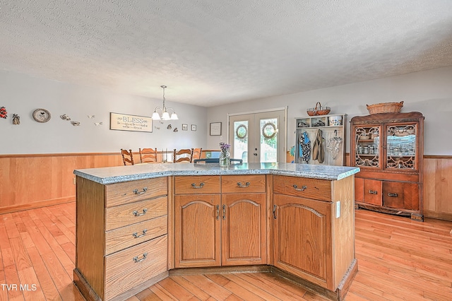 481 Pleasant Hill Rd, Blountville, TN 37617 - kitchen with light wood-style flooring, a textured ceiling, a wainscoted wall, a chandelier, and french doors