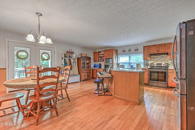 481 Pleasant Hill Rd, Blountville, TN 37617 - kitchen with stainless steel appliances, a textured ceiling, a center island, brown cabinetry, and light wood-style flooring