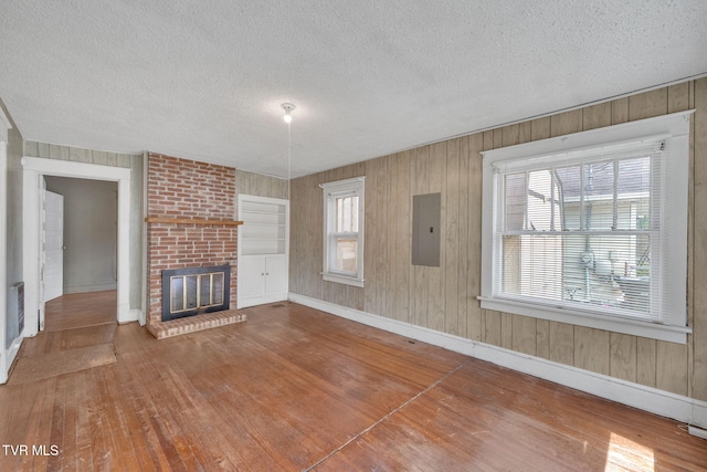 1217 Kentucky Ave, Bristol, TN 37620 - unfurnished living room with electric panel, hardwood / wood-style floors, a textured ceiling, baseboards, and a brick fireplace