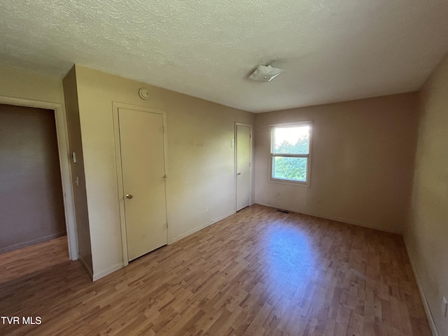 12139 Driffield Dr, Coeburn, VA 24230 - unfurnished bedroom with light wood-style floors, baseboards, a textured ceiling, and a closet