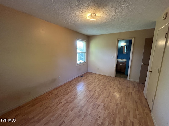 12139 Driffield Dr, Coeburn, VA 24230 - unfurnished bedroom featuring light wood-style floors, a textured ceiling, baseboards, and connected bathroom