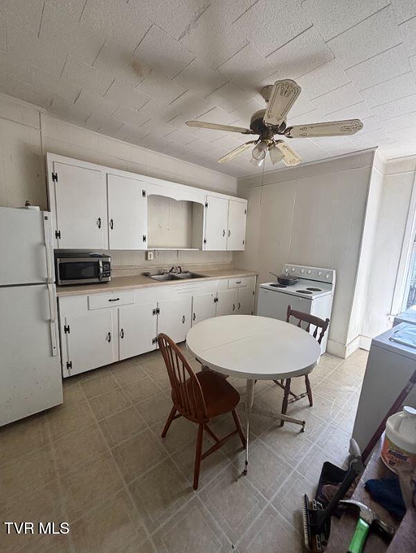 501 Moore St, Bristol, VA 24201 - kitchen featuring freestanding refrigerator, stainless steel microwave, white cabinets, a sink, and ceiling fan