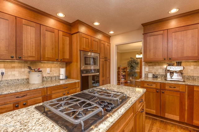 22319 Campground Rd, Bristol, VA 24202 - kitchen featuring oven, black gas stovetop, stainless steel microwave, brown cabinetry, and ornamental molding