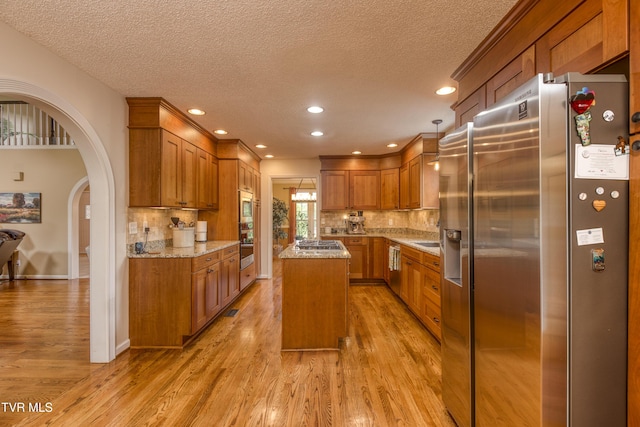 22319 Campground Rd, Bristol, VA 24202 - kitchen with appliances with stainless steel finishes, brown cabinetry, a textured ceiling, arched walkways, and light wood-style flooring