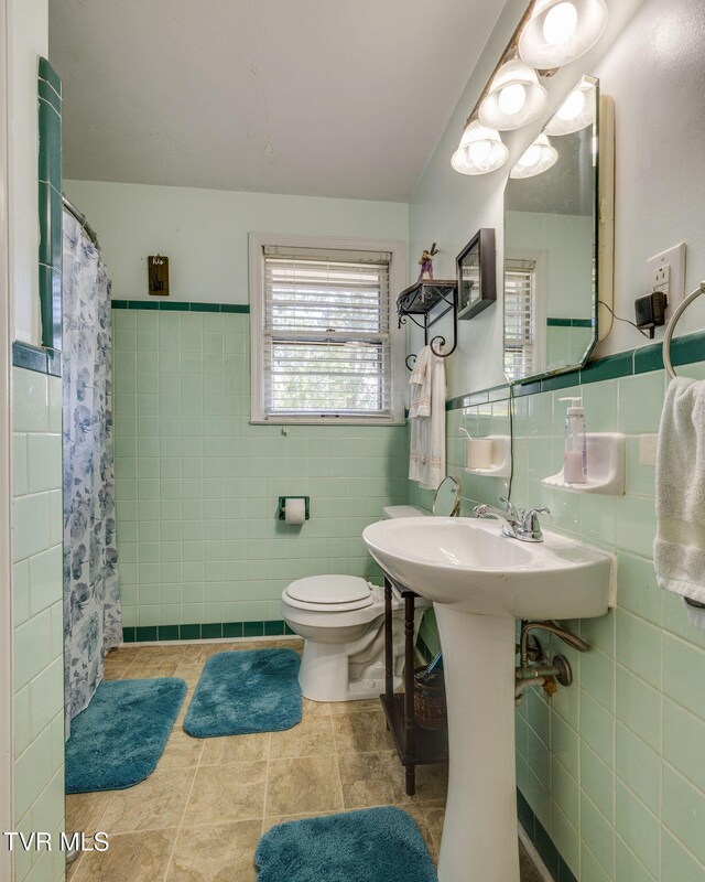 2228 Bruce St, Kingsport, TN 37664 - bathroom featuring tile walls, toilet, a shower with shower curtain, and a wainscoted wall