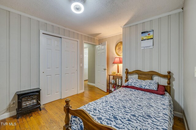 2228 Bruce St, Kingsport, TN 37664 - bedroom with ornamental molding, a wood stove, wood finished floors, a textured ceiling, and a closet