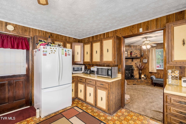 293 Miller Rd, Jonesborough, TN 37659 - kitchen featuring freestanding refrigerator, wooden walls, stainless steel microwave, ceiling fan, and a wood stove