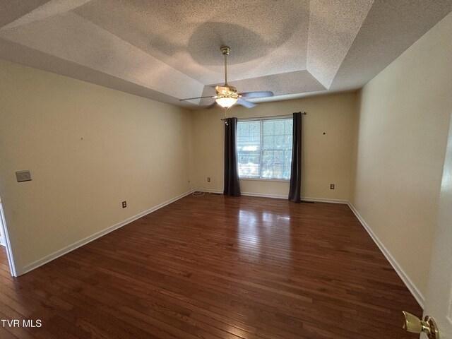 115 Butterfly Ct, Limestone, TN 37681 - empty room featuring a tray ceiling, a textured ceiling, dark wood-style flooring, a ceiling fan, and baseboards