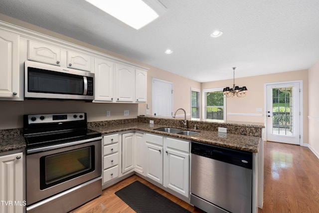1010 Appaloosa Trl, Johnson City, TN 37604 - kitchen featuring appliances with stainless steel finishes, a sink, a chandelier, a peninsula, and light wood-type flooring