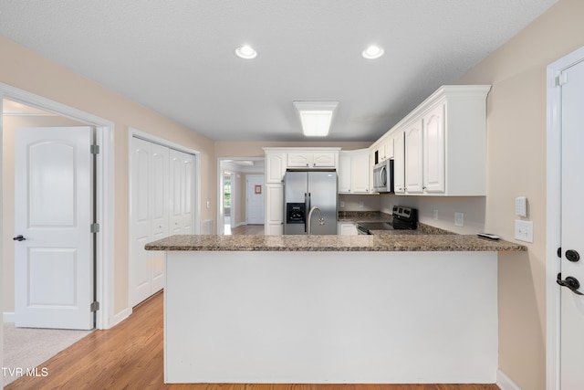 1010 Appaloosa Trl, Johnson City, TN 37604 - kitchen with stainless steel appliances, a peninsula, white cabinets, a sink, and dark stone counters
