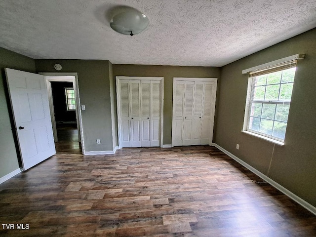 226 Heritage Hills Dr, Greeneville, TN 37745 - unfurnished bedroom with multiple closets, dark wood-type flooring, baseboards, and a textured ceiling