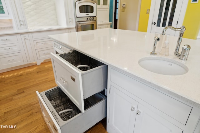 133 Knob Creek Dock Rd, Johnson City, TN 37601 - kitchen featuring a sink, double wall oven, white cabinetry, light wood-type flooring, and light stone countertops