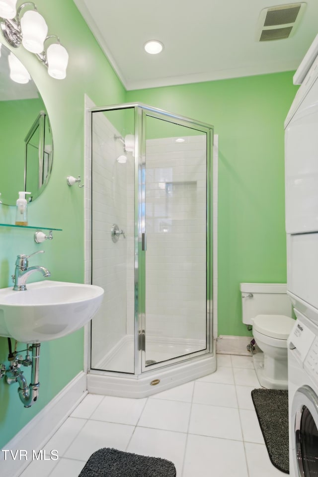 133 Knob Creek Dock Rd, Johnson City, TN 37601 - bathroom featuring stacked washing machine and dryer, tile patterned flooring, toilet, a shower stall, and baseboards