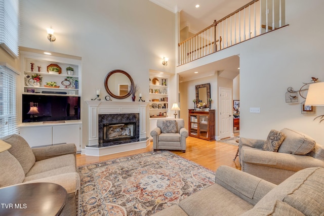 117 Quail Heights Ct, Kingsport, TN 37663 - living room featuring built in shelves, wood finished floors, a high ceiling, a premium fireplace, and crown molding