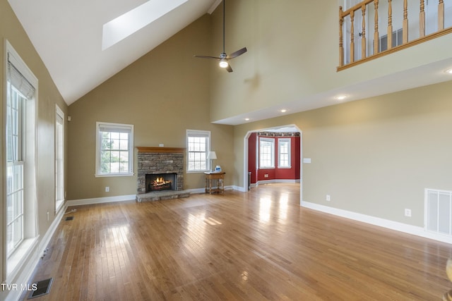 2361 Old Stage Rd, Afton, TN 37616 - unfurnished living room with a towering ceiling, light wood-style flooring, a fireplace, a skylight, and baseboards