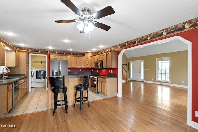 2361 Old Stage Rd, Afton, TN 37616 - kitchen with stainless steel appliances, washing machine and clothes dryer, a sink, dark countertops, and a kitchen island