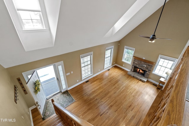 2361 Old Stage Rd, Afton, TN 37616 - unfurnished living room featuring a skylight, high vaulted ceiling, wood finished floors, baseboards, and a fireplace