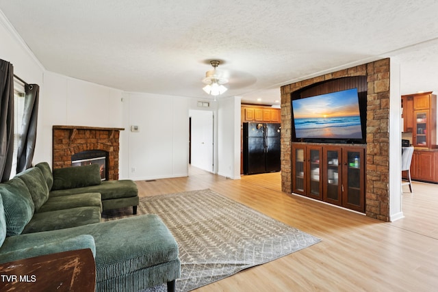 364 Berry Ridge Rd, Jonesborough, TN 37659 - living room featuring light wood-style flooring, a textured ceiling, ceiling fan, and a stone fireplace