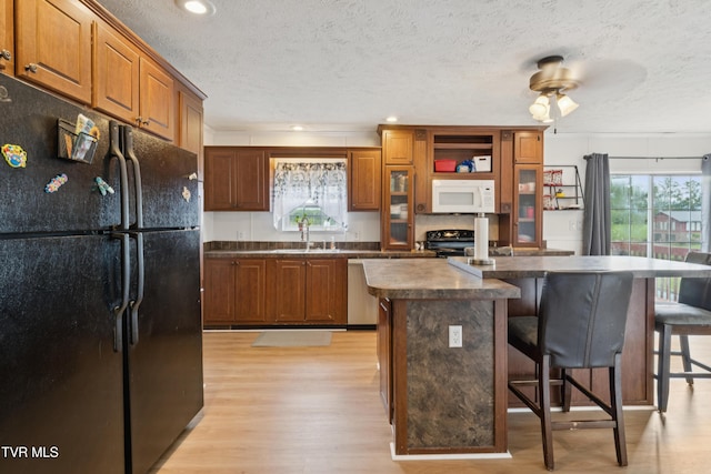 364 Berry Ridge Rd, Jonesborough, TN 37659 - kitchen featuring black appliances, dark countertops, light wood-style flooring, a kitchen breakfast bar, and a textured ceiling