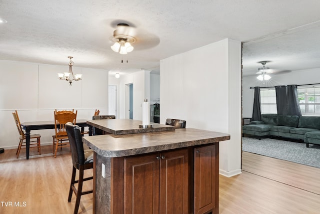364 Berry Ridge Rd, Jonesborough, TN 37659 - kitchen with a ceiling fan, dark countertops, light wood-style floors, a textured ceiling, and a kitchen breakfast bar