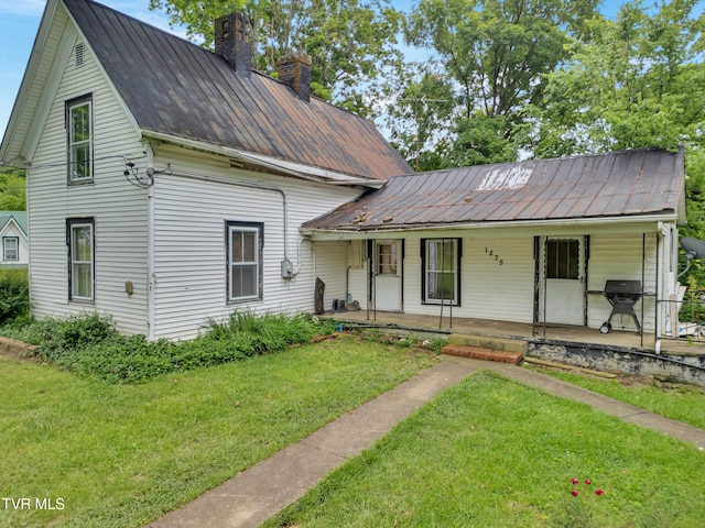 1275 Chuckey Pike, Chuckey, TN 37641 - view of front of house featuring a chimney, a porch, a front yard, and metal roof