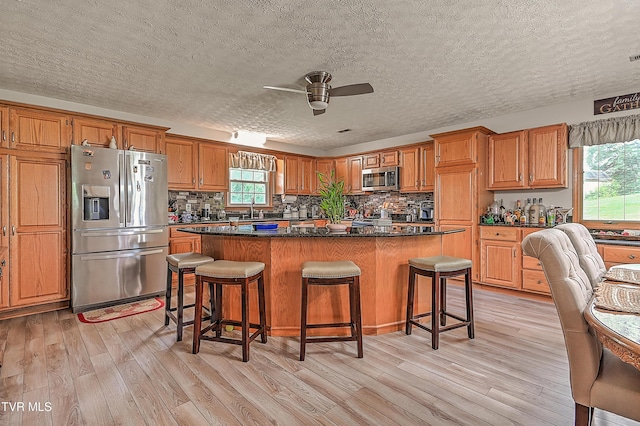 205 Live Oak Dr, Kingsport, TN 37660 - kitchen featuring stainless steel appliances, light wood-style flooring, a ceiling fan, a center island, and a textured ceiling