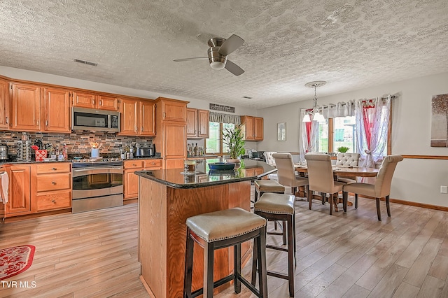 205 Live Oak Dr, Kingsport, TN 37660 - kitchen featuring stainless steel appliances, light wood-type flooring, a kitchen breakfast bar, dark countertops, and ceiling fan