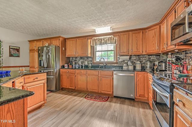 205 Live Oak Dr, Kingsport, TN 37660 - kitchen with stainless steel appliances, a sink, a textured ceiling, light wood-type flooring, and tasteful backsplash