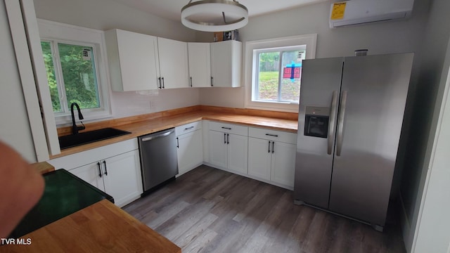 616 6th St, Bristol, TN 37620 - kitchen featuring appliances with stainless steel finishes, an AC wall unit, a sink, dark wood-type flooring, and white cabinets