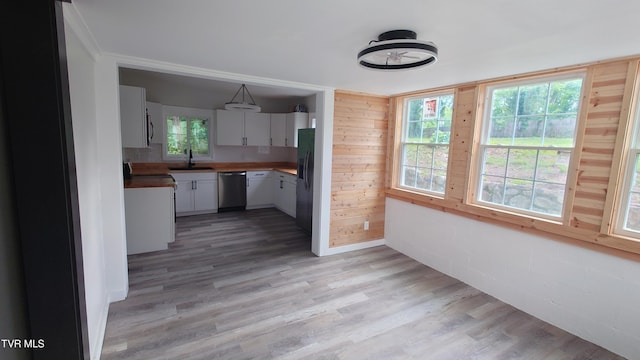 616 6th St, Bristol, TN 37620 - kitchen featuring appliances with stainless steel finishes, a sink, light wood-type flooring, white cabinets, and wood walls