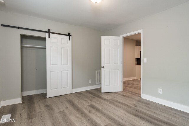 1605 E Fairview Ave, Johnson City, TN 37601 - unfurnished bedroom with wood finished floors, a barn door, baseboards, and a closet