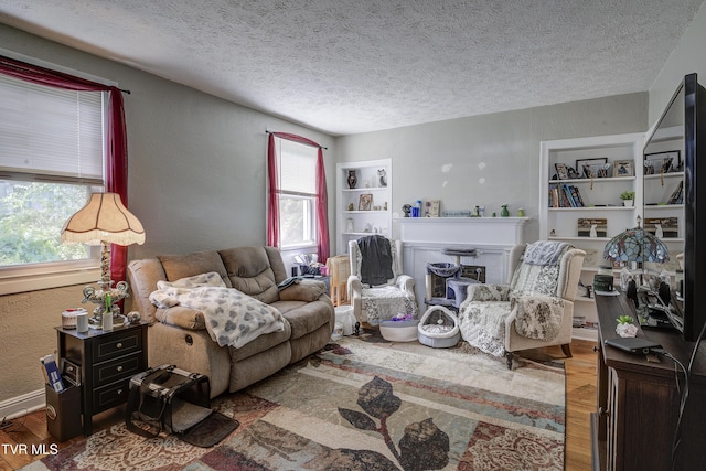 1321 Pineola Ave, Kingsport, TN 37664 - living room featuring wood finished floors, plenty of natural light, a textured ceiling, a glass covered fireplace, and a textured wall